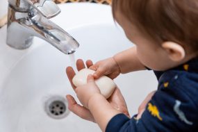 Toddler washing hands with soap and water