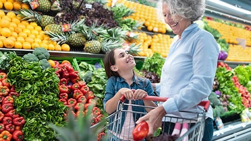 — title missing — Grandmother and child shopping for fruits and vegetables in grocery.
