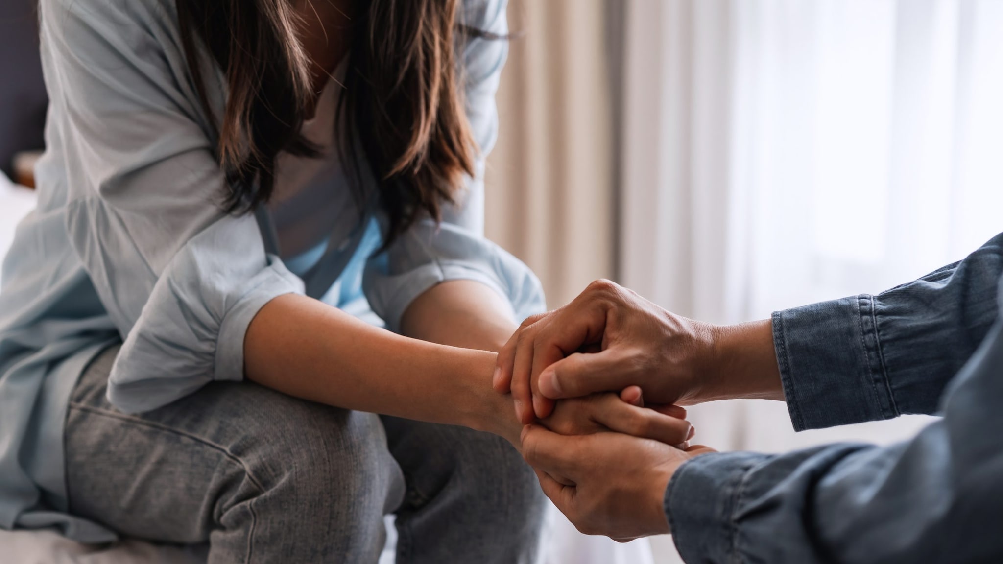 A man comforts a woman by holding her hands.