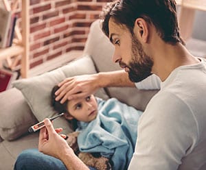 Father checking the temperature of his daughter with a cold.