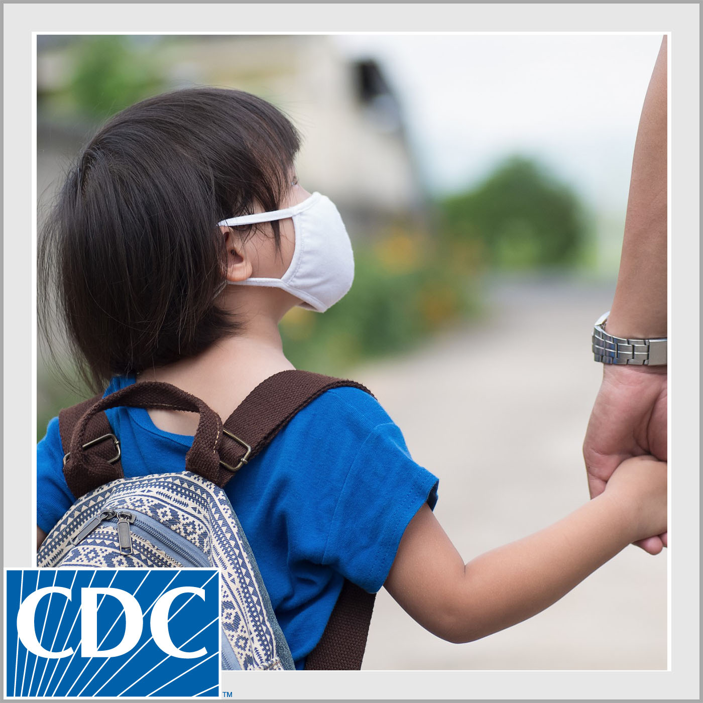 Child wearing a backpack holding parent's hand