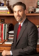 Sam-Posner A photograph of Dr Samuel F. Posner appears behind a desk in front of a bookshelf.