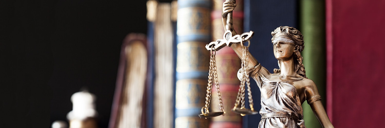 Lady justice statue holding scales with books in the background Lady justice statue holding scales with books in the background