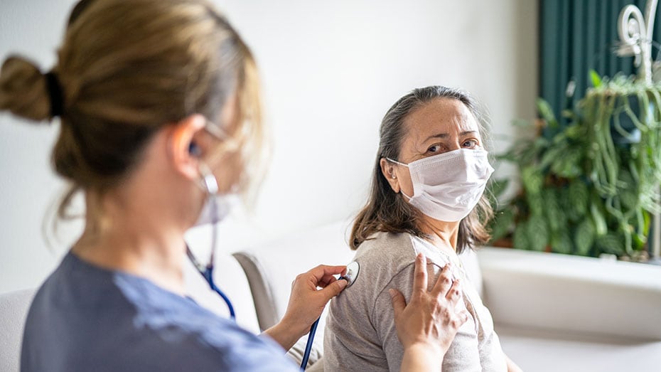 — title missing — A healthcare worker listens to a patient's lungs.