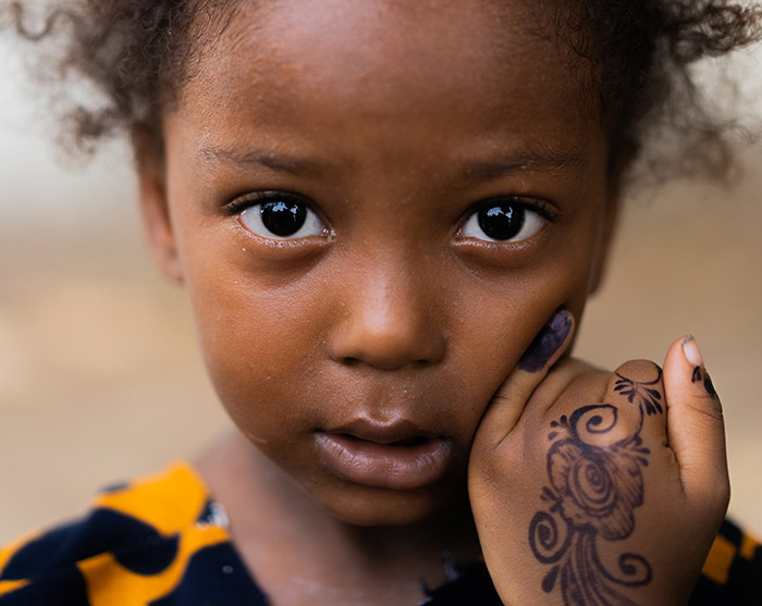 A young girl shows the purple mark on her pinky finger indicating she received a polio vaccine.