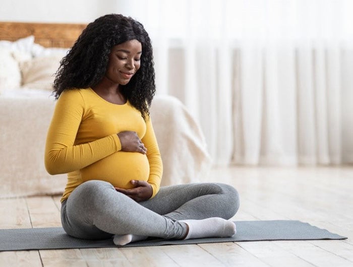Pregnant African American women on exercise mat Pregnant African American women on exercise mat