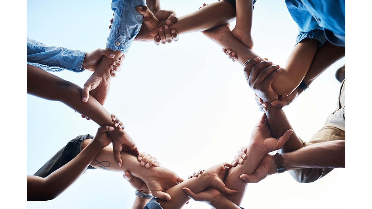 — title missing — Image, from below, of people linking arms to create a circle.