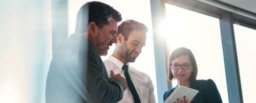 Three people reviewing data on a tablet device