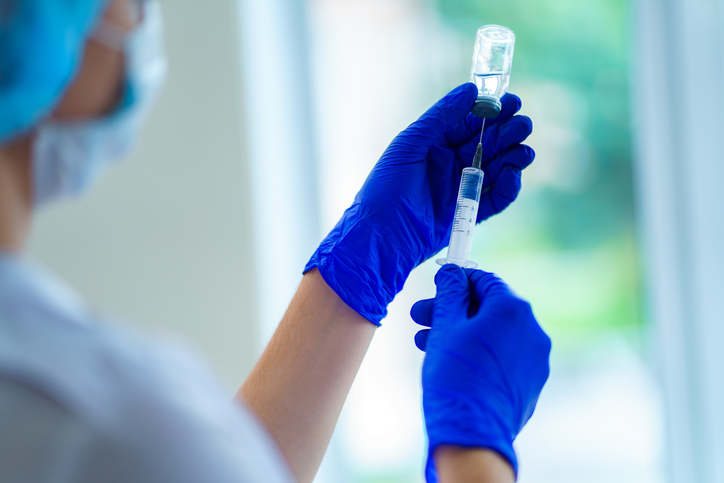 healthcare worker in full PPE preparing a vaccine