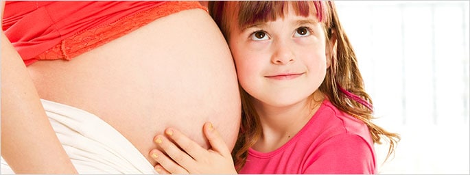 Little girl embracing her pregnant mother