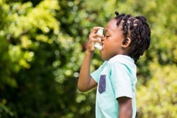 — title missing — A child uses an asthma inhaler.