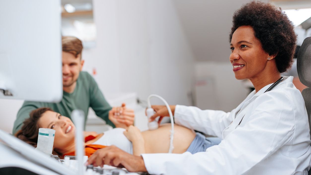 Monitor Doctor performing an ultrasound on a pregnant patient