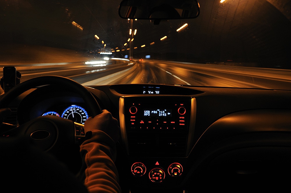 Drowsy driving is more common at night Photo of hands on a steering wheel of a car, driving at night.