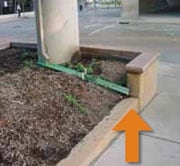 Tubería de desagüe exterior abriéndose dentro de un tubo de plástico que desvía el agua hacia la acera inclinada