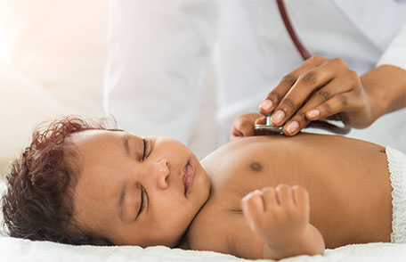 Un médico examinando a un bebé con un estetoscopio.