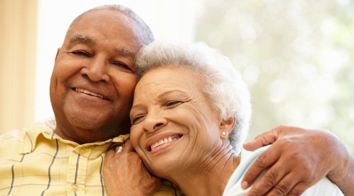 Una pareja mayor abrazándose y sonriendo.