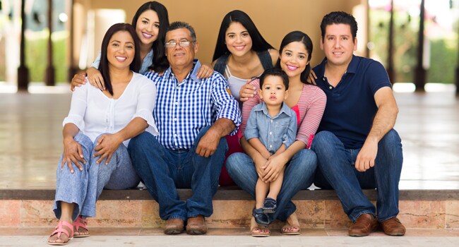 vacunas-informese-650px.jpg Familia latina, padres, hijos, abuelos y nietos sentados sonriendo.