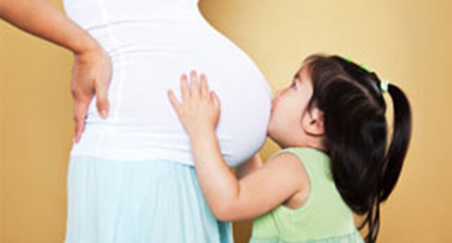 Vacunas para las madres: Parte de un embarazo saludable Niña besando el estómago de su madre embarazada