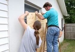 Hombres cubriendo ventanas con tablas Hombres cubriendo ventanas con tablas