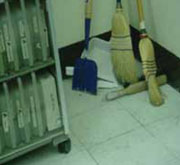 Escobas y recogedor recostados en la esquina de una habitación