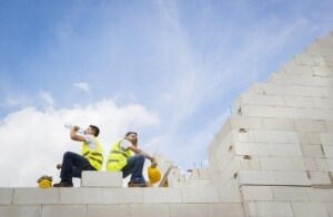 Dos trabajadores de la construcción sentados durante un descanso y bebiendo agua Dos trabajadores de la construcción sentados durante un descanso y bebiendo agua