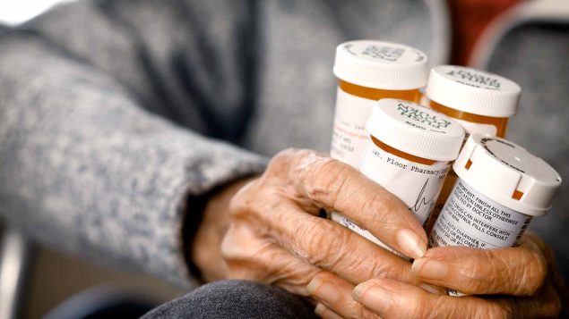An older adult holding several bottles of pills
