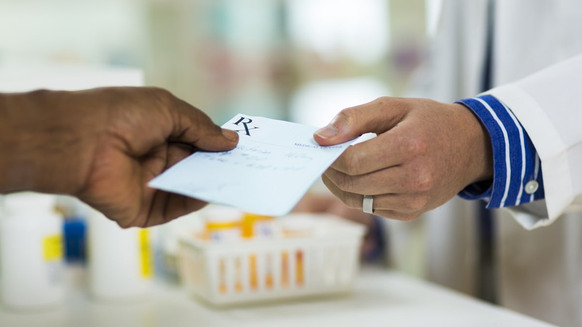 prescription photo Photo of a person handing a prescription slip to a pharmacist.