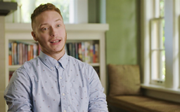 video-3 Hispanic transman sitting in room with bookcase behind him talking to camera