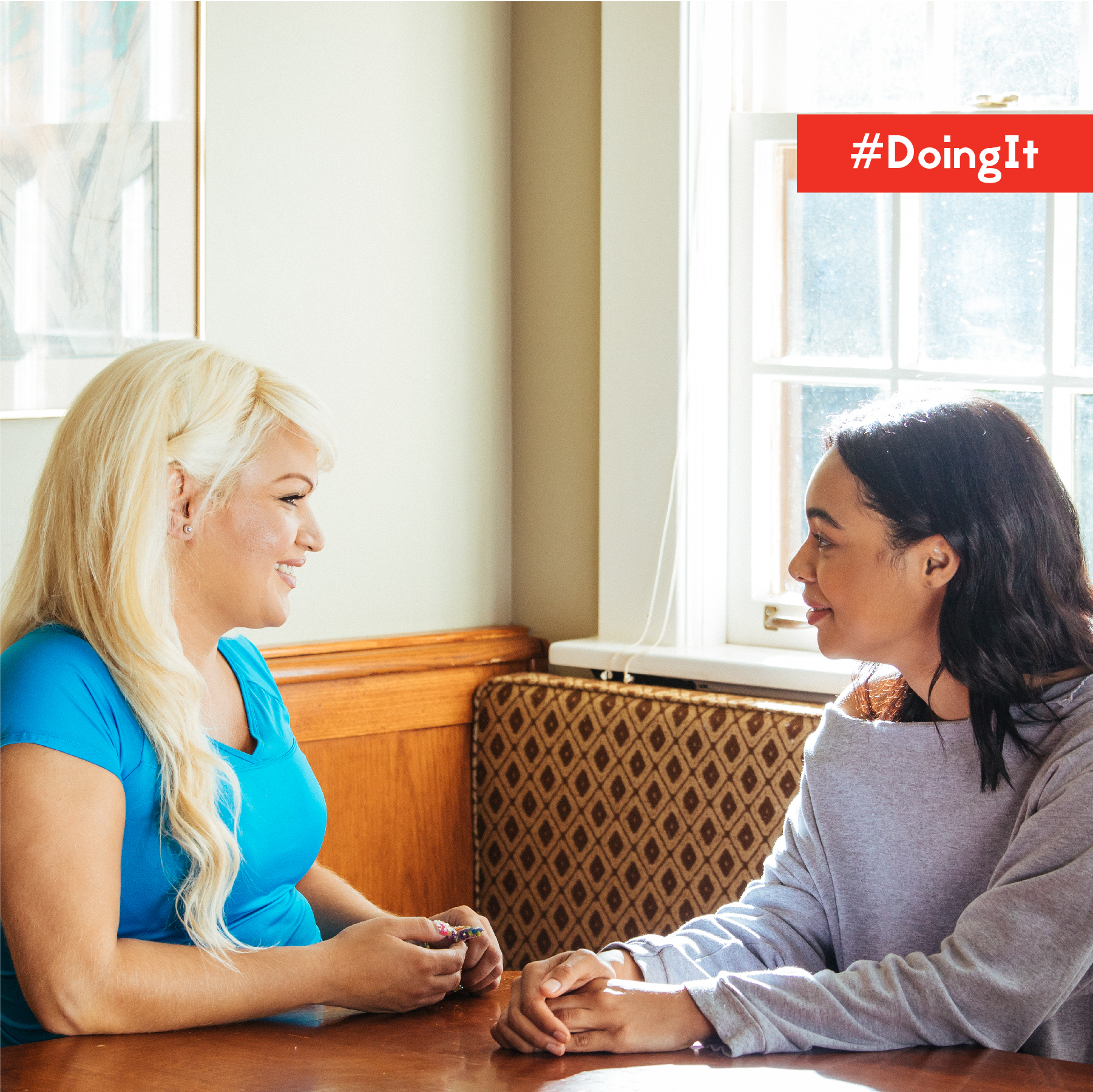 two-women-sitting Image displays two women sitting at a table engaged in a friendly conversation.