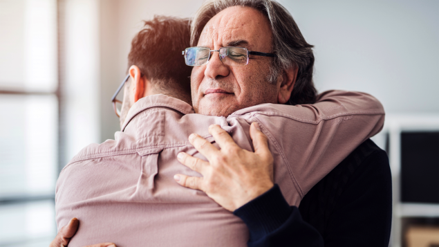 Two middle aged adult men hugging