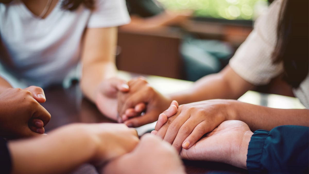 — title missing — four people clasping hands