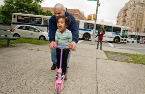 father teaching little girl to ride a bike