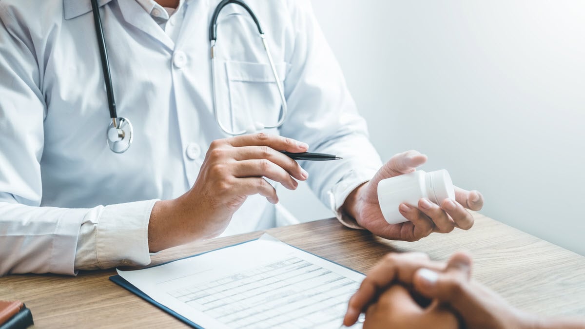 Doctor giving patient medicine Doctor holding a white pill bottle and talking about medicine with a patient with no face visible