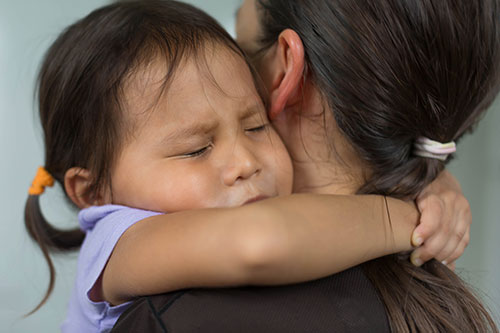 scared asian child hugging parent