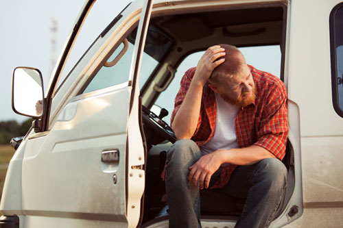 Regional man sitting Photo of a man sitting on a van with its door open.