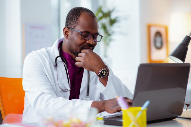 Dark-skinned doctor wearing glasses and watch feeling though…