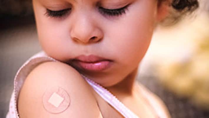 Little girl with band-aid on arm A little girl looking at the band-aid on her right shoulder from where she got a vaccine.