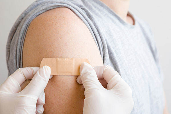 Hands applying bandage to patient's shoulder