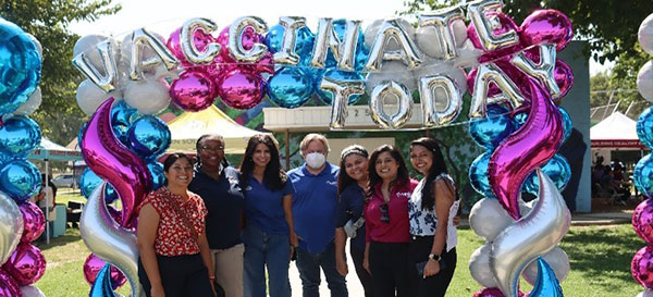 Group of people standing under Vaccinate Today sign