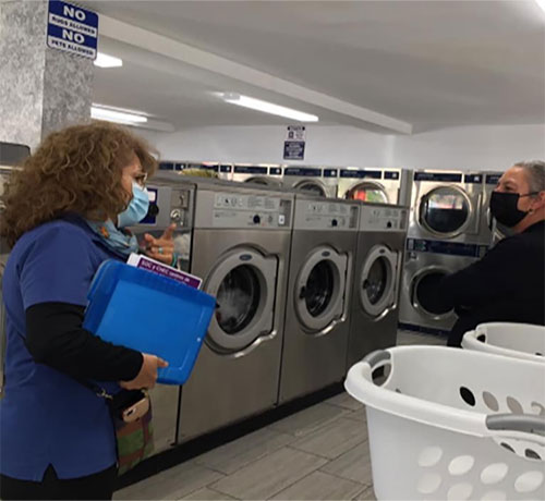 latino-health-access-image3 Worker approaches woman in a laundromat