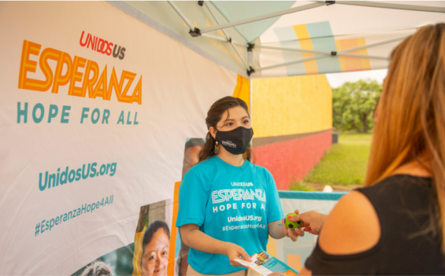 mobile-clinic Latina woman in a mask handing out information at a mobile vaccination clinic.