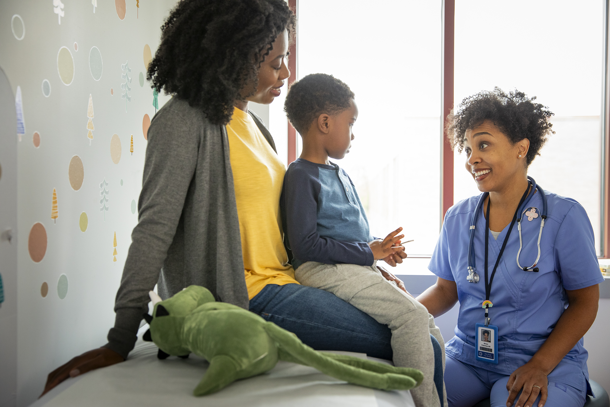 Pediatric patient and parent talking to healthcare provider in a medical office.