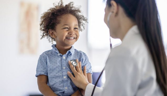 An Asian American female doctor and a young African American boy patient