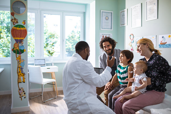 doctor-family-records African American doctor talking to white family with a young son and infant.