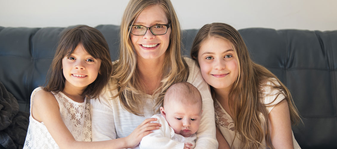 Madre sentanda con sus hijas y su bebé