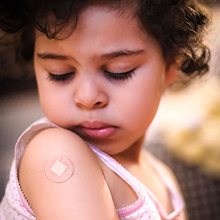 girl-arm-bandage Little girl looking at a small bandage on her shoulder