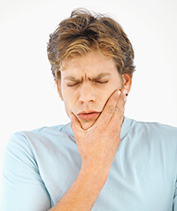 man-holding-cheek.jpg Front view of young man holding his cheek in pain.