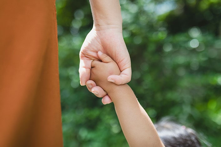 mother-daughter-hands Madre e hija cogidas de la mano en el parque.