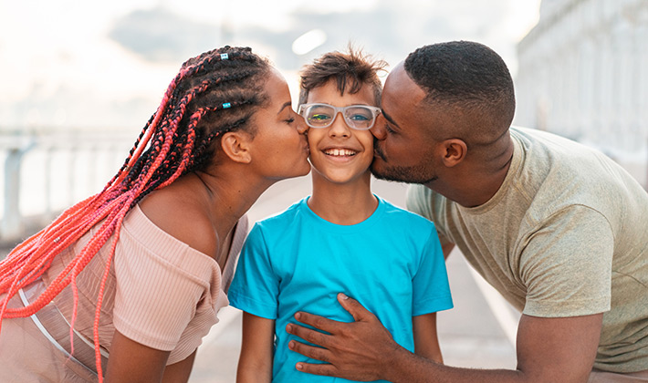 Parents kissing their son outdoors