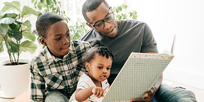Dad reading a book for his kids at home